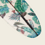 A close-up of a Surf Thump longboard decorated with a vibrant tropical pattern featuring green leaves and colorful flowers on a white background, perfect for those seeking versatile handling on the waves.
