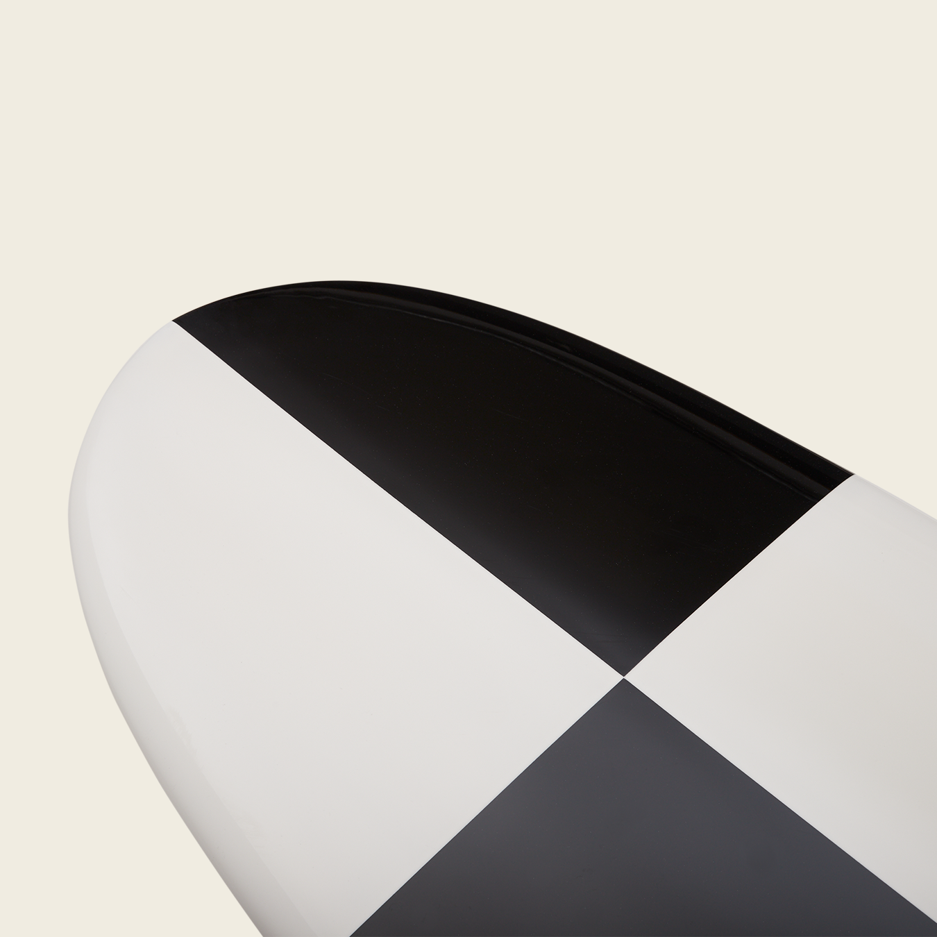 Close-up of the end of a traditional surfboard featuring a bold black and white checkered pattern on a plain, light background—perfect for classic noseriding style.