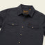 A dark navy Sawhorse Work Shirt with two front chest pockets, each secured by a snap button. The rugged cotton shirt features a pointed collar, gold snap buttons down the front, and a small HOWLER tag on the left pocket.
