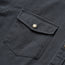 Close-up of a dark gray herringbone Sawhorse Work Shirt, featuring a buttoned flap chest pocket with visible stitching and a silver metal button.