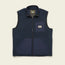 A navy blue Chisos Fleece Vest with a front zipper, two lower front pockets, and a chest pocket featuring a rectangular “Howler Brothers” logo patch. This lightweight vest has a high collar and contrasting high pile fleece fabric panels.