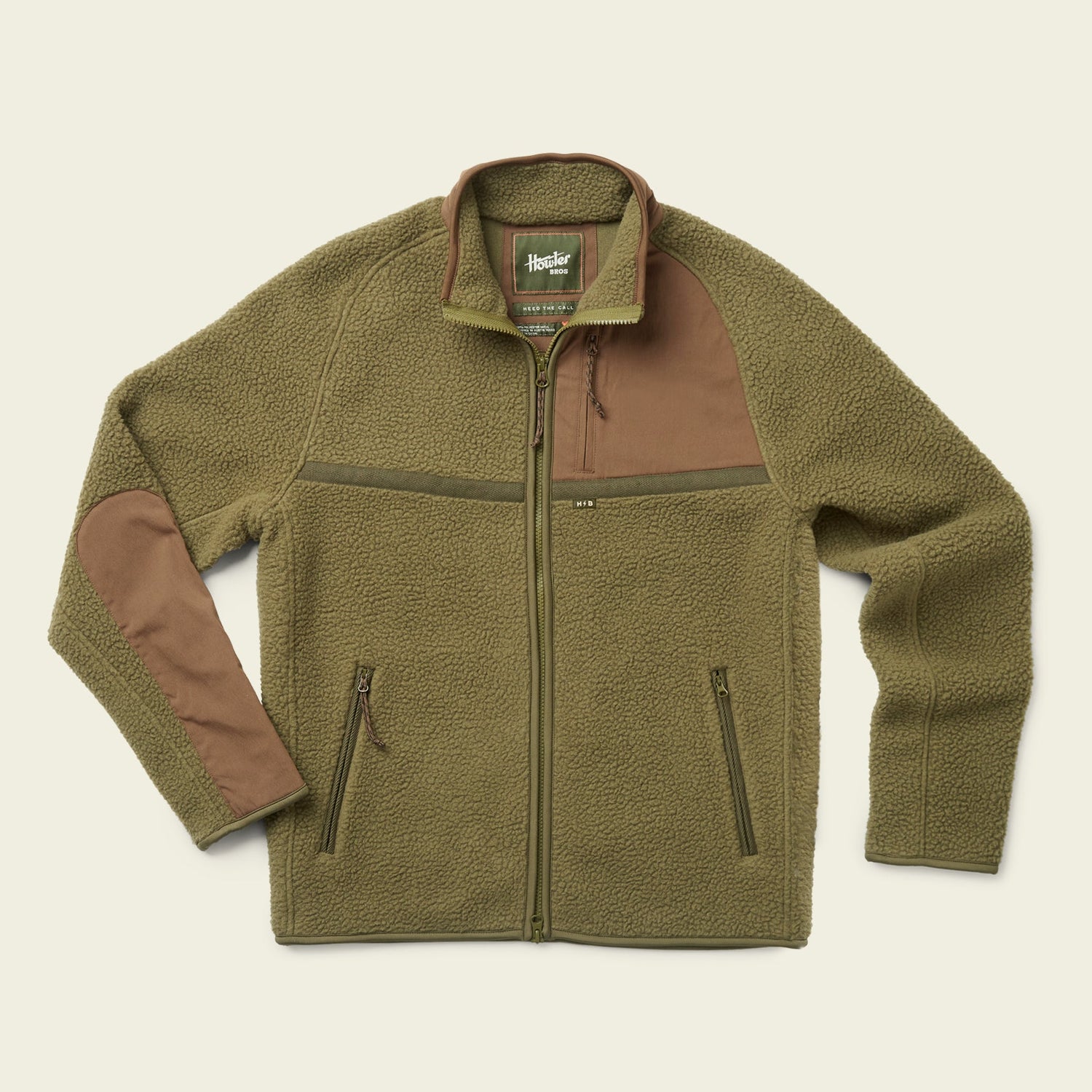Olive green polyester fleece jacket with a full front zipper, two zippered side pockets, brown fabric patches on the right shoulder and left elbow, and a green collar with a branded label inside—essential fall outerwear.