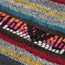 A close-up of a woven jacquard hoodie fabric with colorful horizontal stripes in gray, red, yellow, blue, brown, orange, pink, and white, showing a textured and detailed pattern.