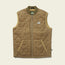 A brown quilted vest with PrimaLoft Gold Insulation, front zipper, two side pockets, ribbed collar, and a small rectangular Howler Bros patch on the left chest. The lightweight layering piece is laid flat on a light neutral background.