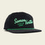 A black corduroy unstructured snapback baseball cap with green trim and embroidered text reading Somos Verdes and Howler Bros on the front, part of the 2024 Verde Collection inspired by Austin FC. The background is a light beige color.