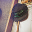 A black Unstructured Snapback corduroy cap with green embroidery reading Somos Verdes from the 2024 Verde Collection rests on a pinball machine, with a pool cue nearby—showcasing Austin FC spirit.