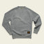 A light gray, long-sleeve crewneck sweatshirt with a soft, textured fabric. It features ribbed cuffs and hem, and a black and gold “Howler Brothers” patch on the lower left front. The shirt is laid flat on a cream background.