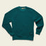A teal fleece crewneck sweatshirt with ribbed cuffs and hem, set against a light beige background. A black and blue rectangular Howler Brothers patch is visible on the lower left side near the hem.