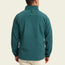 A person wearing a teal fleece pullover and light-colored pants is shown from the back, standing against an off-white background—ideal attire for cold weather.