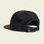A black perforated breathable tech hat with a brown brim, green top button, and an adjustable strap at the back, perfect for outdoor adventures. Shown on a plain light background.