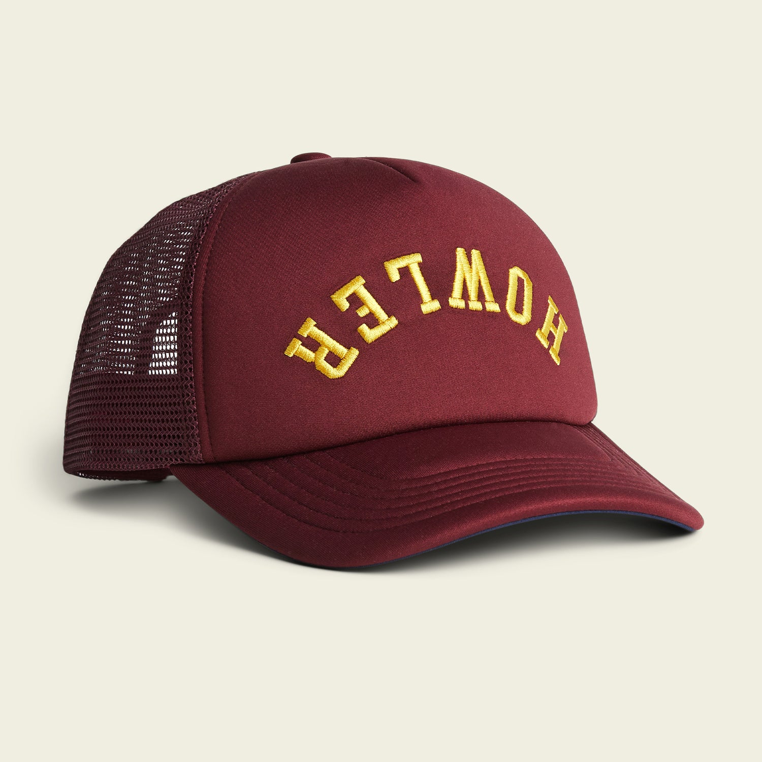 A vintage-inspired, maroon mesh trucker hat with a foam front and the word “HOWLER” embroidered in yellow, upside down, on the high crown front panel.
