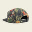 A baseball cap with a colorful, abstract floral pattern features an adjustable snapback closure, small tag with a white logo on the back, and a pliable brim. The unstructured snapback rests on a light, neutral background.