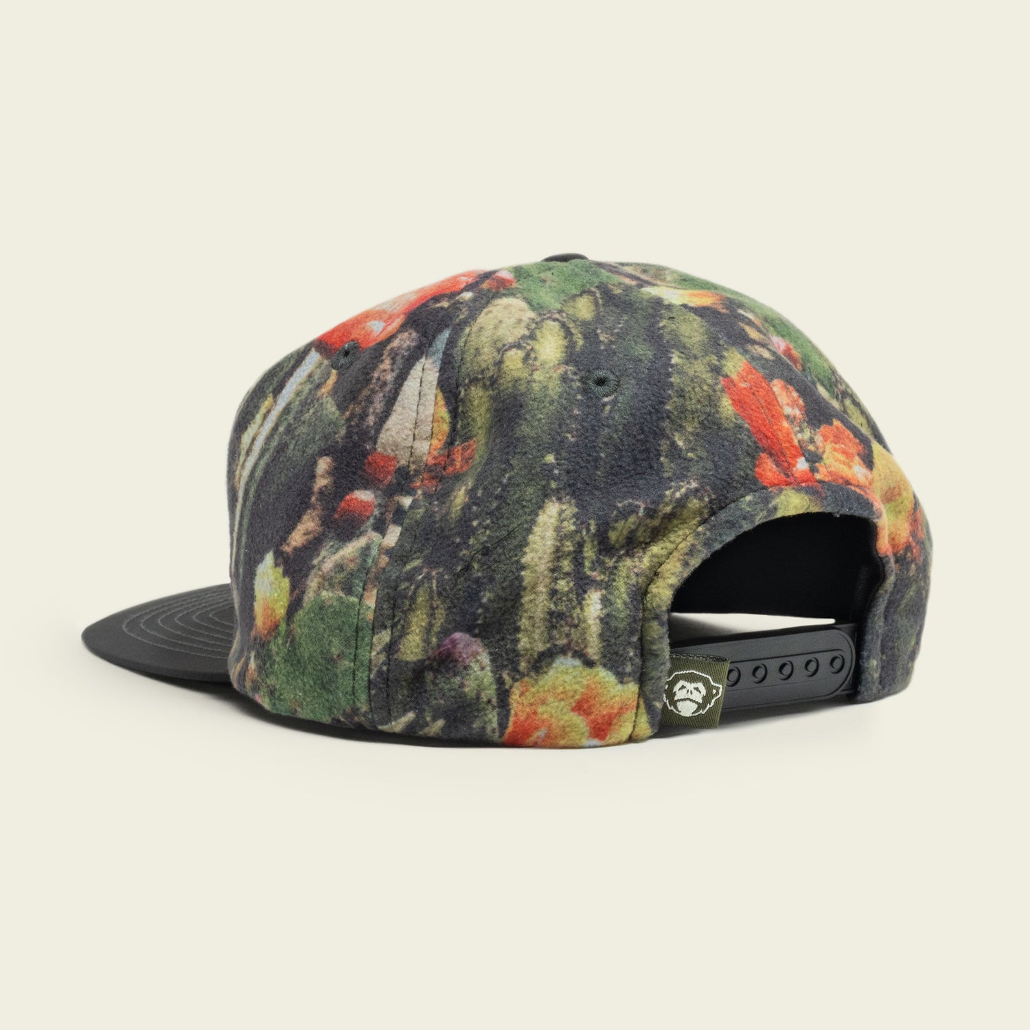 A baseball cap with a colorful, abstract floral pattern features an adjustable snapback closure, small tag with a white logo on the back, and a pliable brim. The unstructured snapback rests on a light, neutral background.