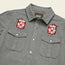 A gray Gaucho Snapshirt with two chest pockets and embroidered red and white Jackson Hole Ski Patrol patches above each pocket, featuring a cross design. The label inside the collar reads Howler Bros.