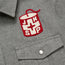 A gray flannel shirt with a buttoned pocket and a patch showing a red can with a white cross and the letters J, H, S, and P—perfect for Jackson Hole Ski Patrol fans.