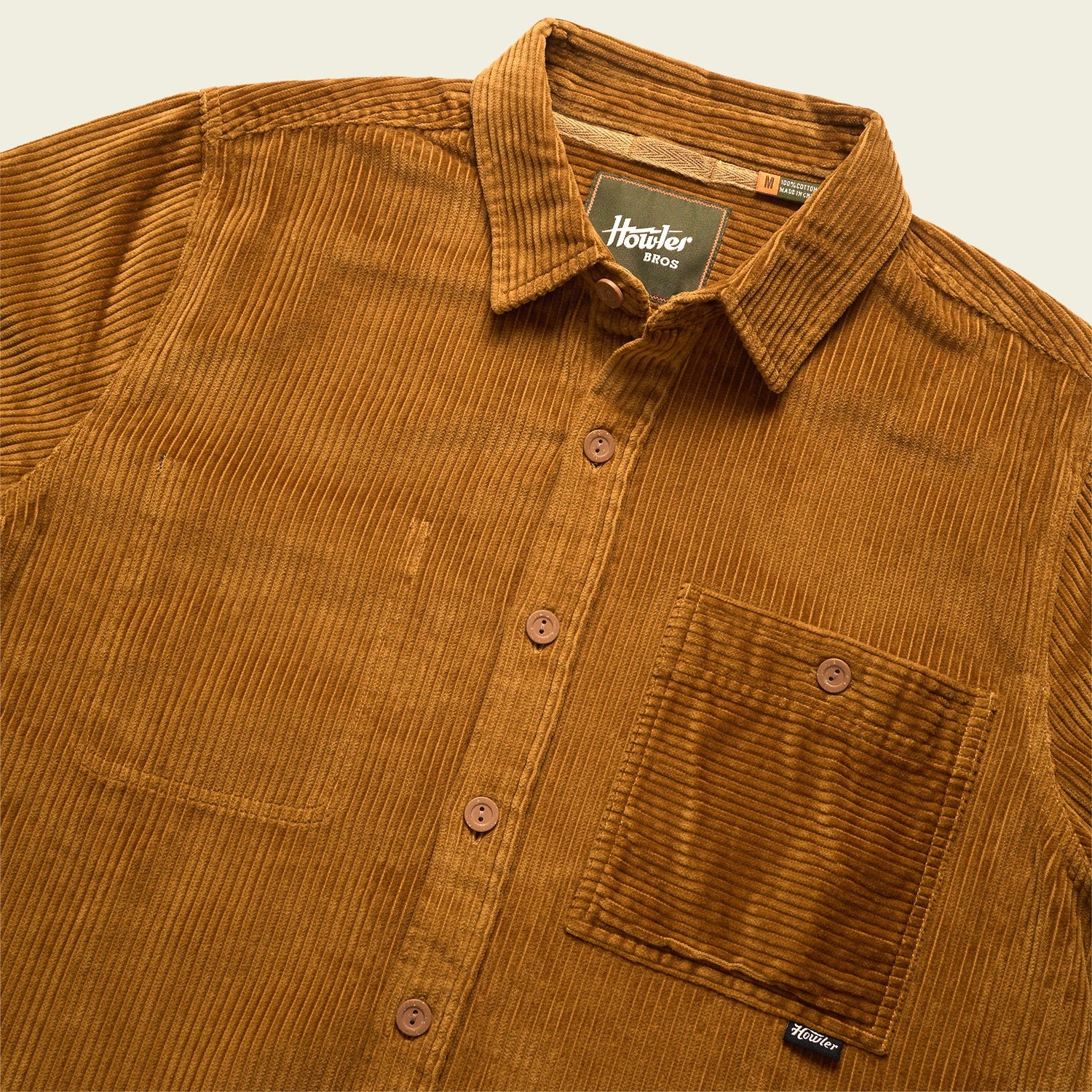 A brown wide wale corduroy button-up shirt with a collar and single chest pocket, featuring brown buttons and a visible Howler Bros label inside the neckline—perfect as an Iquitos Overshirt or travel shirt.