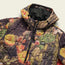 A lightweight travel jacket featuring PrimaLoft insulation, a colorful autumn leaf pattern, front zipper, and small “Howler Brothers” patch on the chest. The quilted jacket is displayed on a light background.