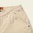 Close-up of beige workwear pants showing the waistband, belt loops, front pocket with metal rivets, and a small fabric tag labeled HTB. Size tags 33 and 32 are visible inside the waistband.