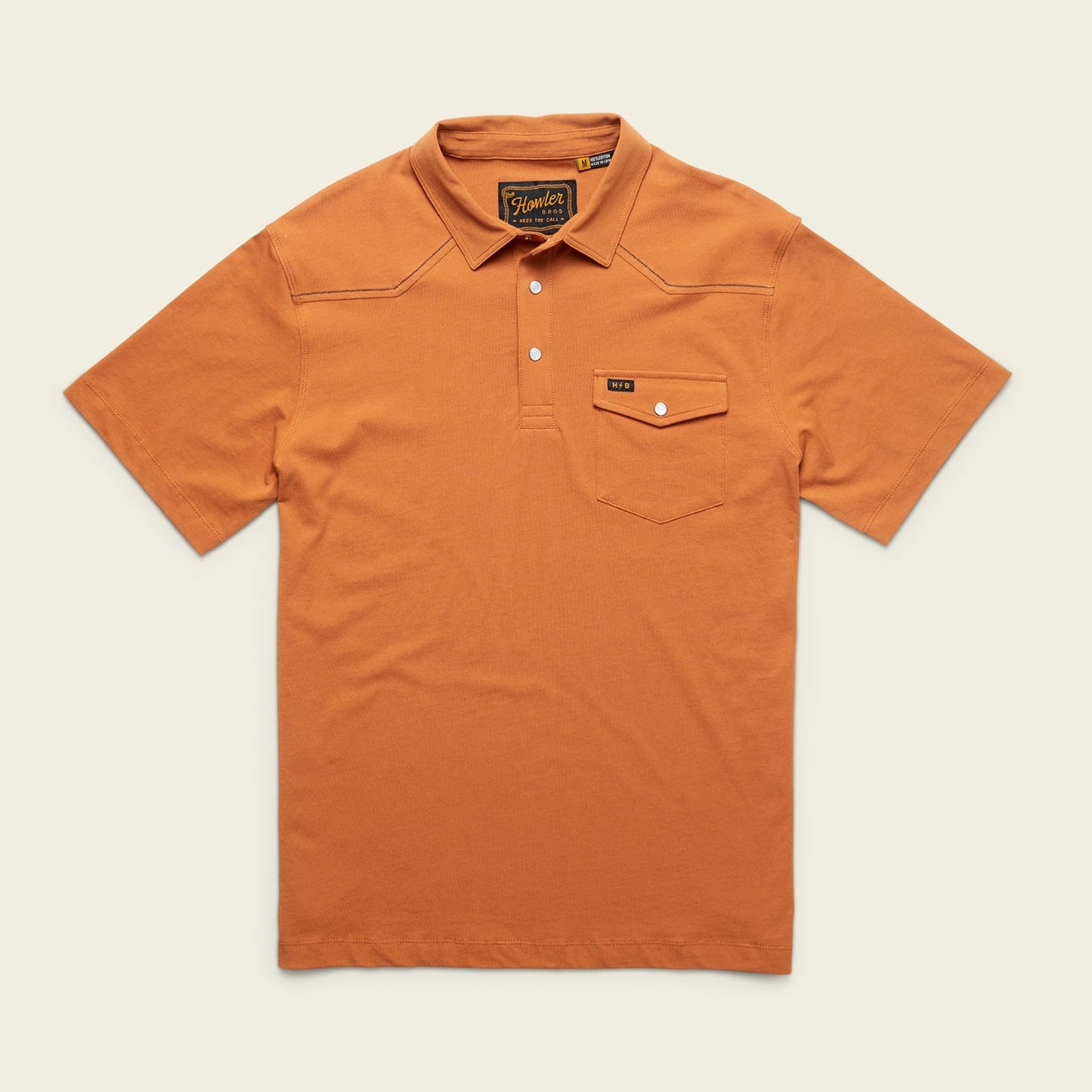 An orange Ranchero Polo, crafted from heathered cotton, features short sleeves, a collar, three buttons, and a button-flap chest pocket with a stitched label—a modern take on a western style polo.