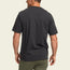 A man is shown from the back wearing a plain black heavyweight cotton t-shirt and olive green pants, standing against a light beige background.