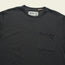 A dark gray Howler Brothers pocket t-shirt made from heavyweight cotton, featuring a chest pocket with a row of small purple geometric shapes along the top edge. The label inside the collar reads Howler.