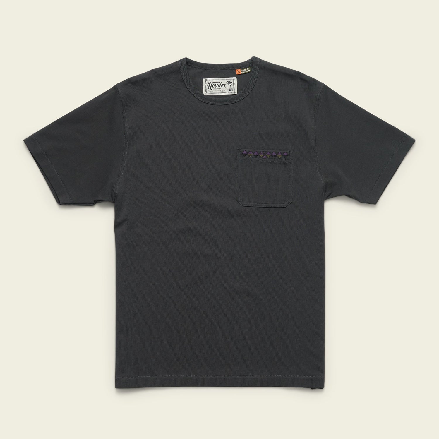 A plain black heavyweight cotton pocket t-shirt with a chest pocket featuring a small patterned strip above it, laid flat on a light background.