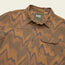 A brown and tan long-sleeve button-up Harkers Flannel shirt with an abstract zigzag pattern, featuring a single chest pocket, collar, and reinforced elbow patches. The tag inside reads Howler Bros.