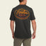 A man wearing a dark gray Howler blended t-shirt with Howler Bros and Welcome to Howler County in orange and yellow script on the back, standing with his back to the camera. Made from a cotton-poly blend for maximum comfort.