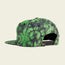 A green and black tie-dye snapback cap shown from the back, featuring an adjustable strap and a small Howler Brothers graphic logo tag next to the closure—a standout piece for snapbacks fans.