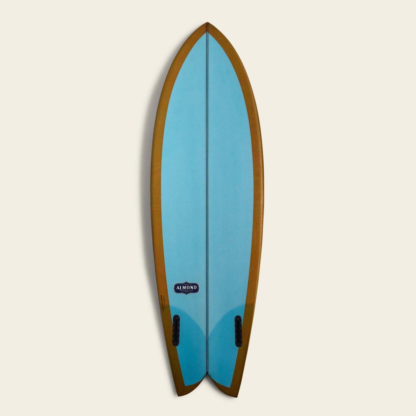 A blue Almond Surfboards surfboard with a brown border and a swallowtail design, displayed vertically against a plain, light background. The board features two black fins and an Almond brand logo near the bottom.