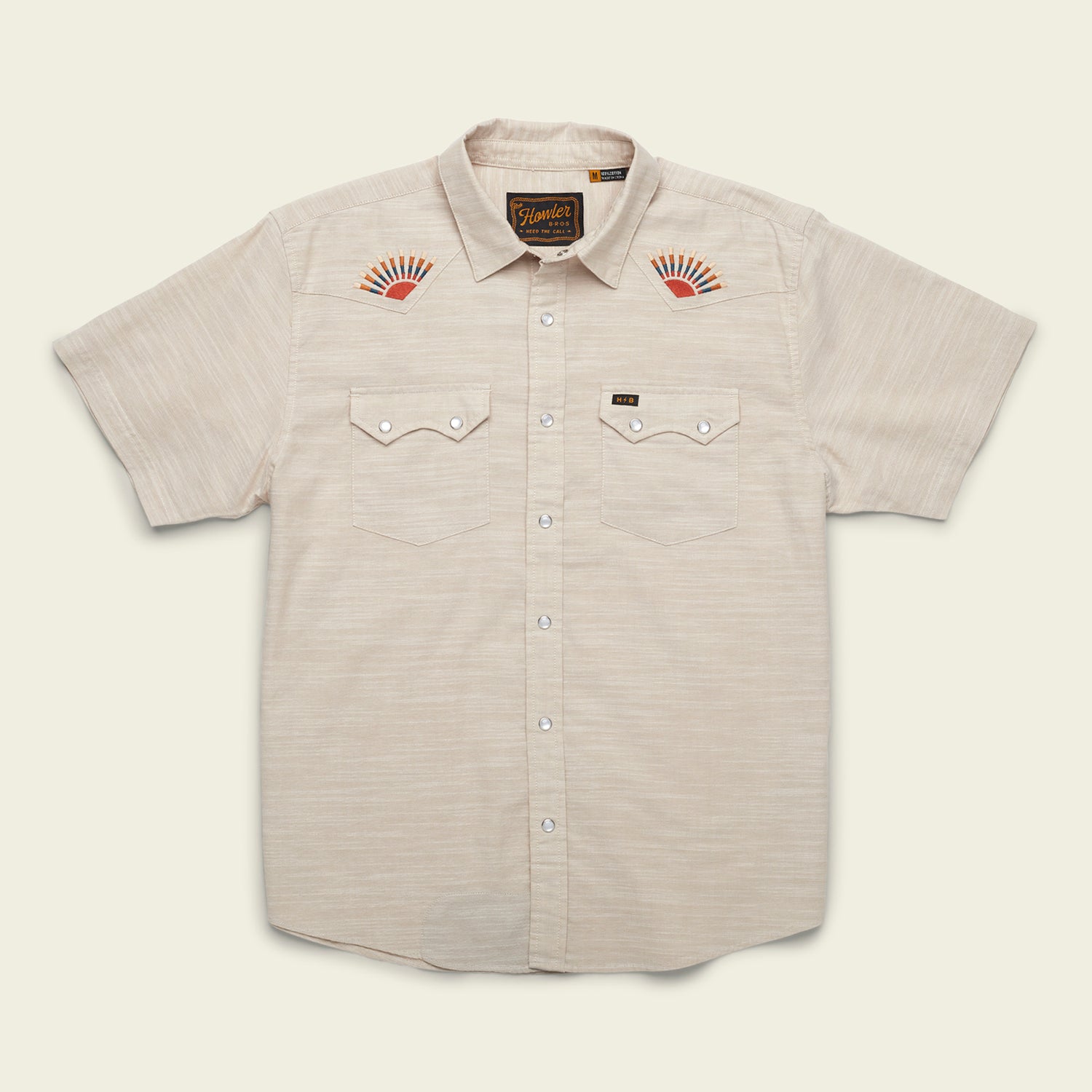 A Crosscut Deluxe Shortsleeve summer shirt in light beige, featuring two front pockets and striking red-orange sunburst motif embroidery on each chest, displayed flat on a pale background.