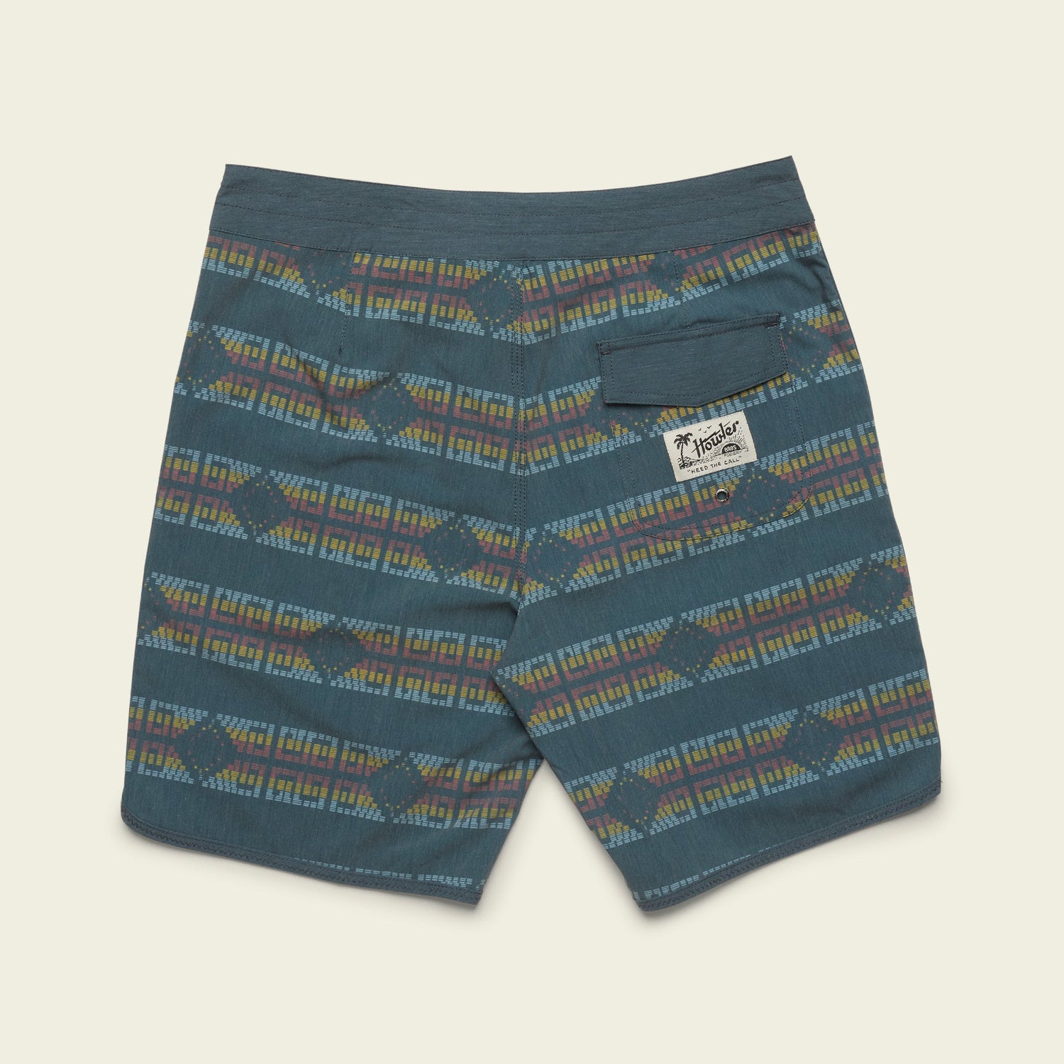 Blue patterned stretchy boardshorts featuring horizontal multicolor geometric designs, a small back pocket with a flap on the right, and a visible white “Jungmaven” brand label below the pocket. The shorts are laid flat on a light background.
