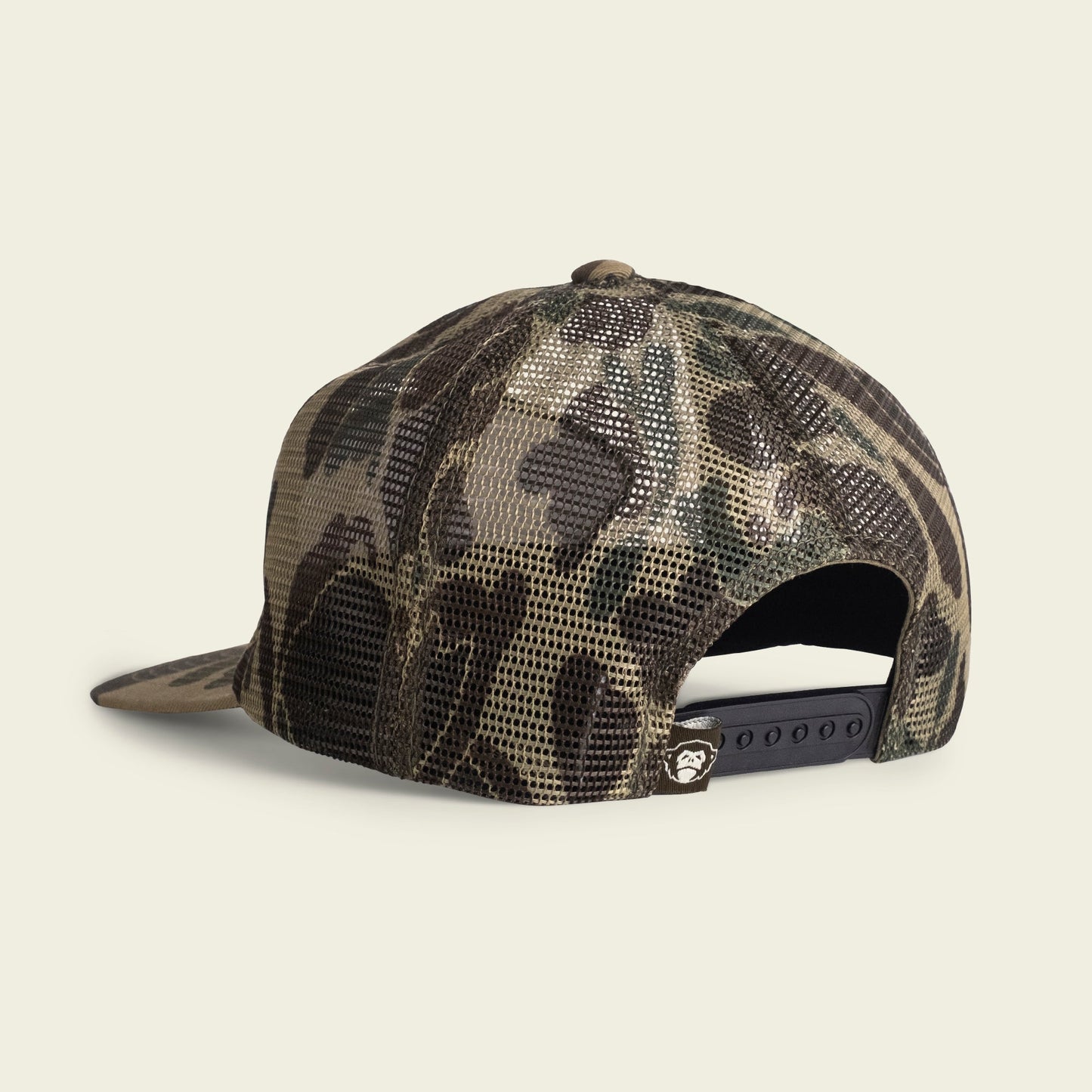A camouflage mesh trucker hat shown from the back, featuring an adjustable snapback closure and a small logo tag above the opening. Its unstructured snapback design offers a relaxed fit with a soft crown.
