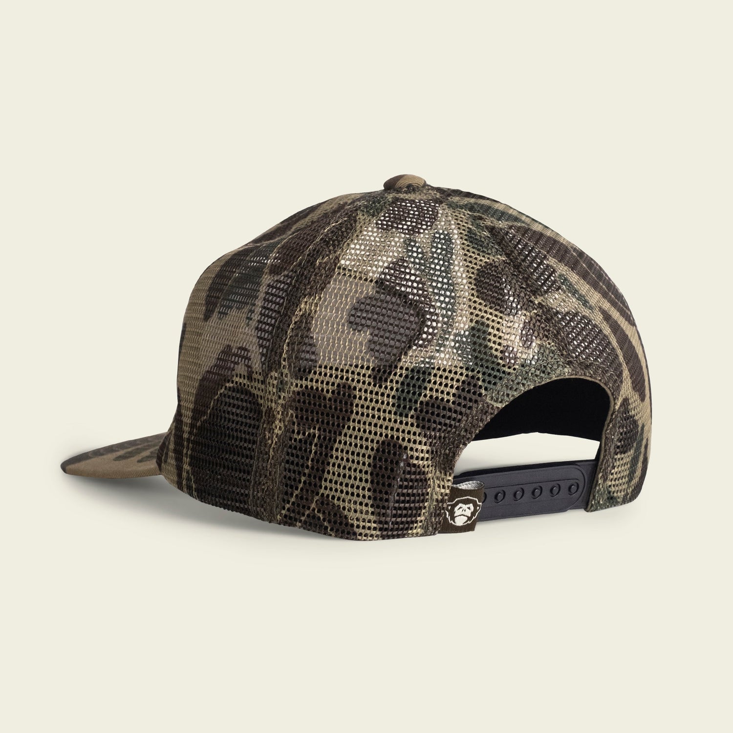 A camouflage mesh trucker hat shown from the back, featuring an adjustable snapback closure and a small logo tag above the opening. Its unstructured snapback design offers a relaxed fit with a soft crown.