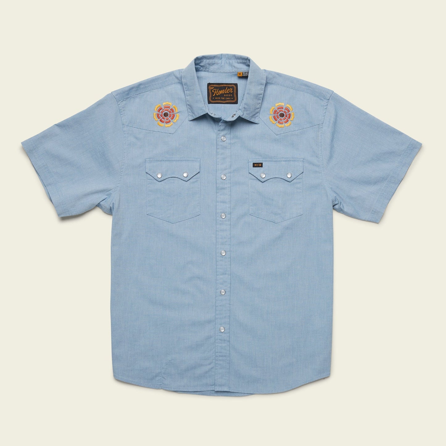 Light blue Crosscut Deluxe Shortsleeve shirt with two chest pockets and motif embroidery of roses on each shoulder. This summer shirt features a casual, western-inspired style and is displayed on a plain background.