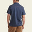 A man is shown from the back, wearing a short-sleeve navy blue Ranchero Polo with a collar, subtle red seam across the upper back, and western yokes. Made from 100% cotton, paired with tan pants against a light beige background.