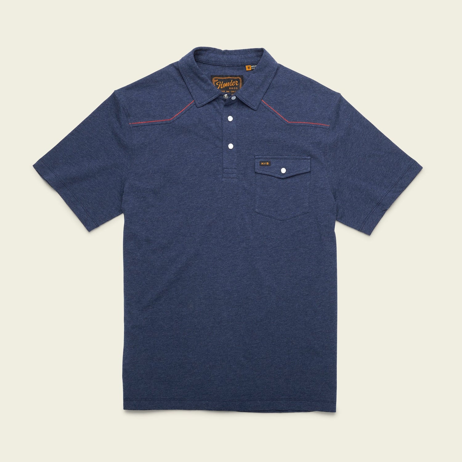 A short-sleeve navy blue Ranchero Polo shirt made from 100% cotton, featuring a button-up collar, front chest pocket with button flap, western yokes, and red stitching detail on the shoulders, laid flat on a light background.
