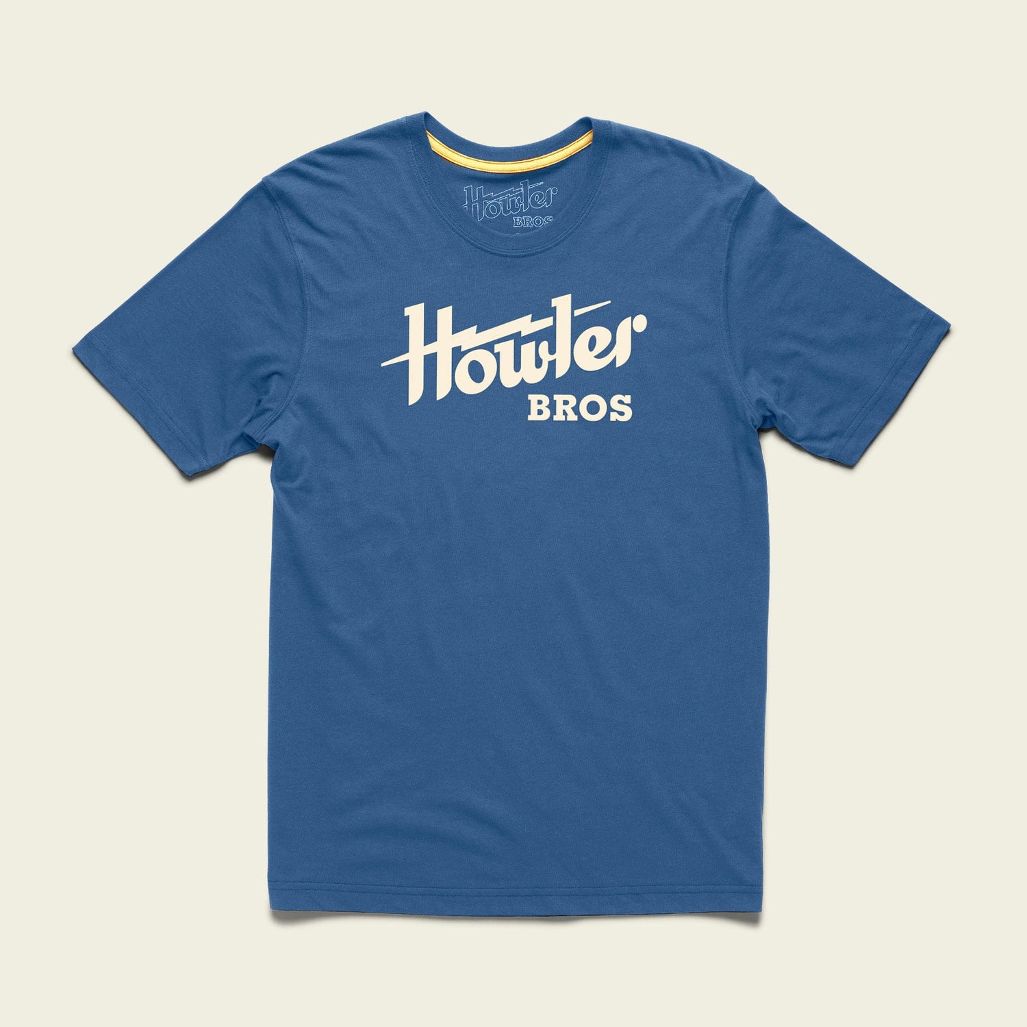 A blue short-sleeve t-shirt made from a soft cotton-poly blend, featuring the bold white Howler Bros logo across the chest. The shirt is laid flat on a light background, showcasing one of the classic Howler designs.