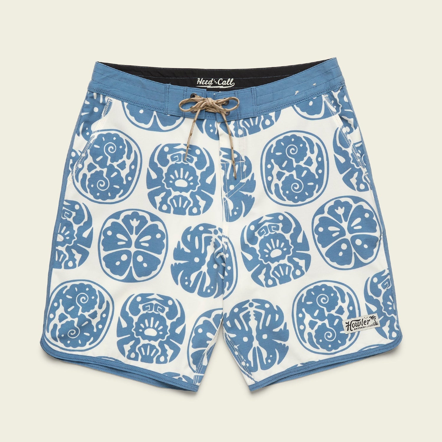 Blue and white Bruja Boardshorts with a drawstring waist, featuring abstract skulls and floral designs. Made from stretchy fabric, these board shorts have a light blue waistband, trim, and a small Howler logo near the left leg hem.