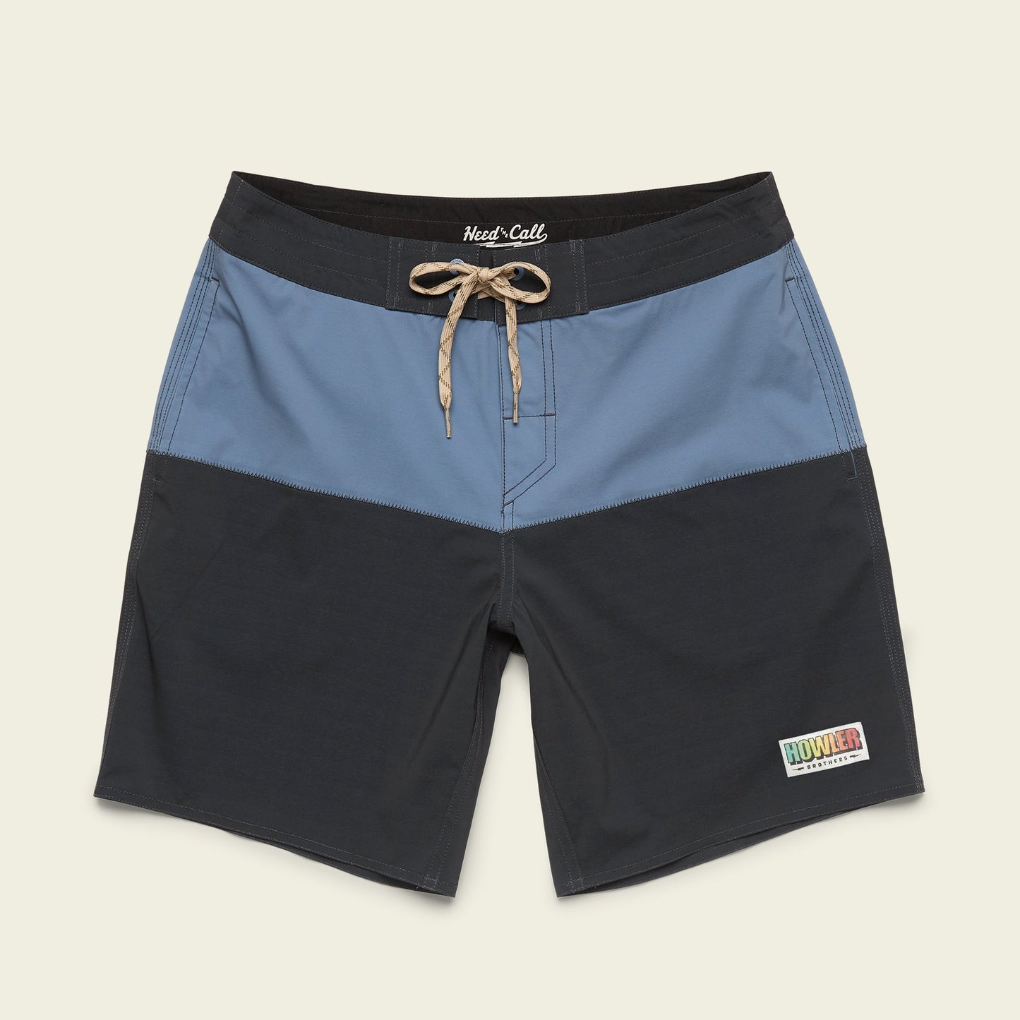 Two-tone Buchannon Boardshorts with a light blue upper and dark gray lower section, tan drawstring waist, quick drying fabric, and a small rectangular Howler patch on the left leg—perfect surf shorts for any adventure.