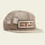 A beige mesh baseball cap with a cream bill, crafted from a quick drying nylon-poly blend, and a rectangular patch on the front that reads HOWLER in orange and brown letters.
