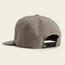 A khaki-colored baseball cap with a soft crown is viewed from the back, featuring an adjustable snapback closure and two ventilation eyelets on each side. The Unstructured Snapback sits against a plain light background.