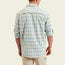 A man is shown from the back wearing a light blue and white plaid Matagorda Shirt with rolled-up sleeves and khaki pants, standing against a plain light background. This travel shirt is quick drying, perfect for any adventure.