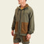 A man wearing a Seabreacher Jacket—an olive green and brown lightweight windbreaker with matching shorts—stands facing slightly left. The water-resistant jacket features a zip front, drawstring hood, and large front pockets. Background is plain and light-colored.