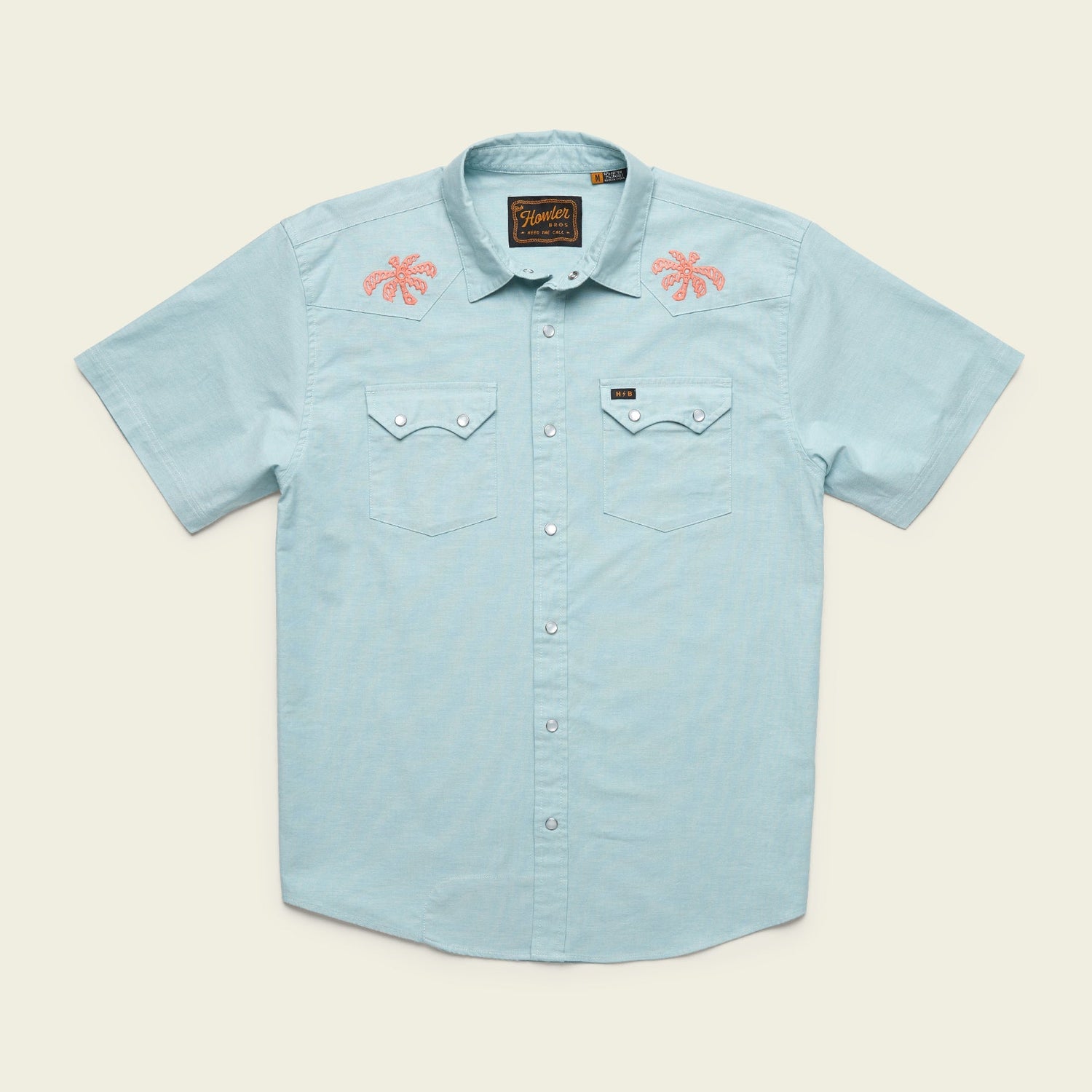 Light blue Crosscut Deluxe Shortsleeve summer shirt with two chest pockets; features pink motif embroidery of palm trees on both shoulders. Shirt is laid flat on a neutral background.
