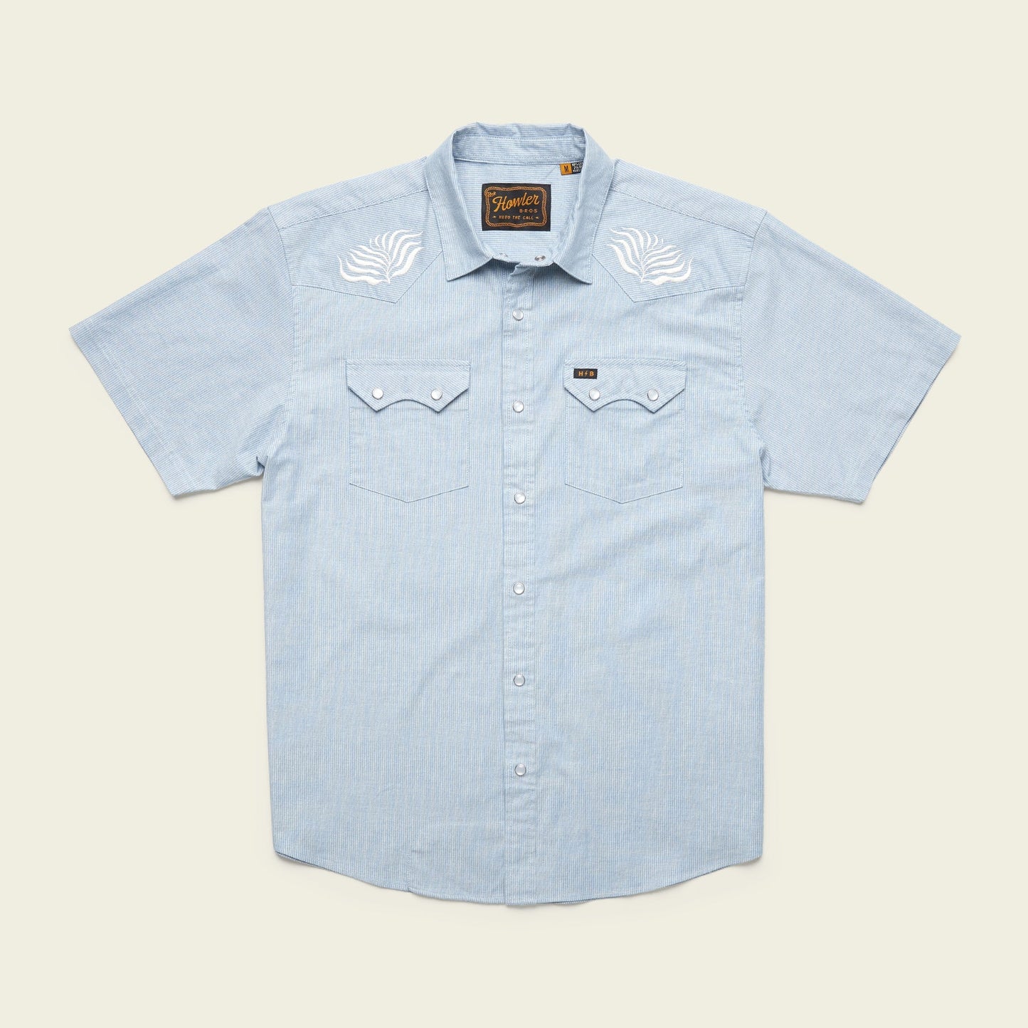 Light blue Crosscut Deluxe Shortsleeve summer shirt with white motif embroidery on the shoulders and two chest pockets with flap closures.