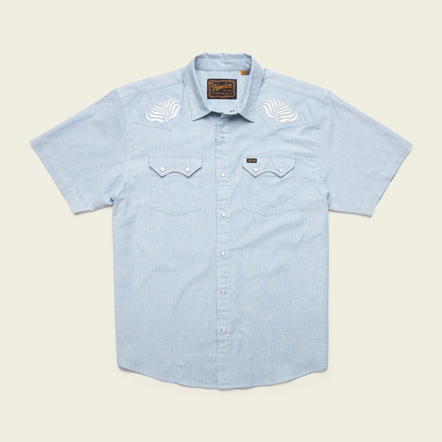Light blue Crosscut Deluxe Shortsleeve summer shirt with white motif embroidery on the shoulders and two chest pockets with flap closures.