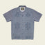 A short-sleeve, button-up blue Guayabera shirt with a subtle geometric pattern, two chest pockets, and unique embroidery, crafted from technical cotton-poly stretch fabric, displayed flat on a neutral background.