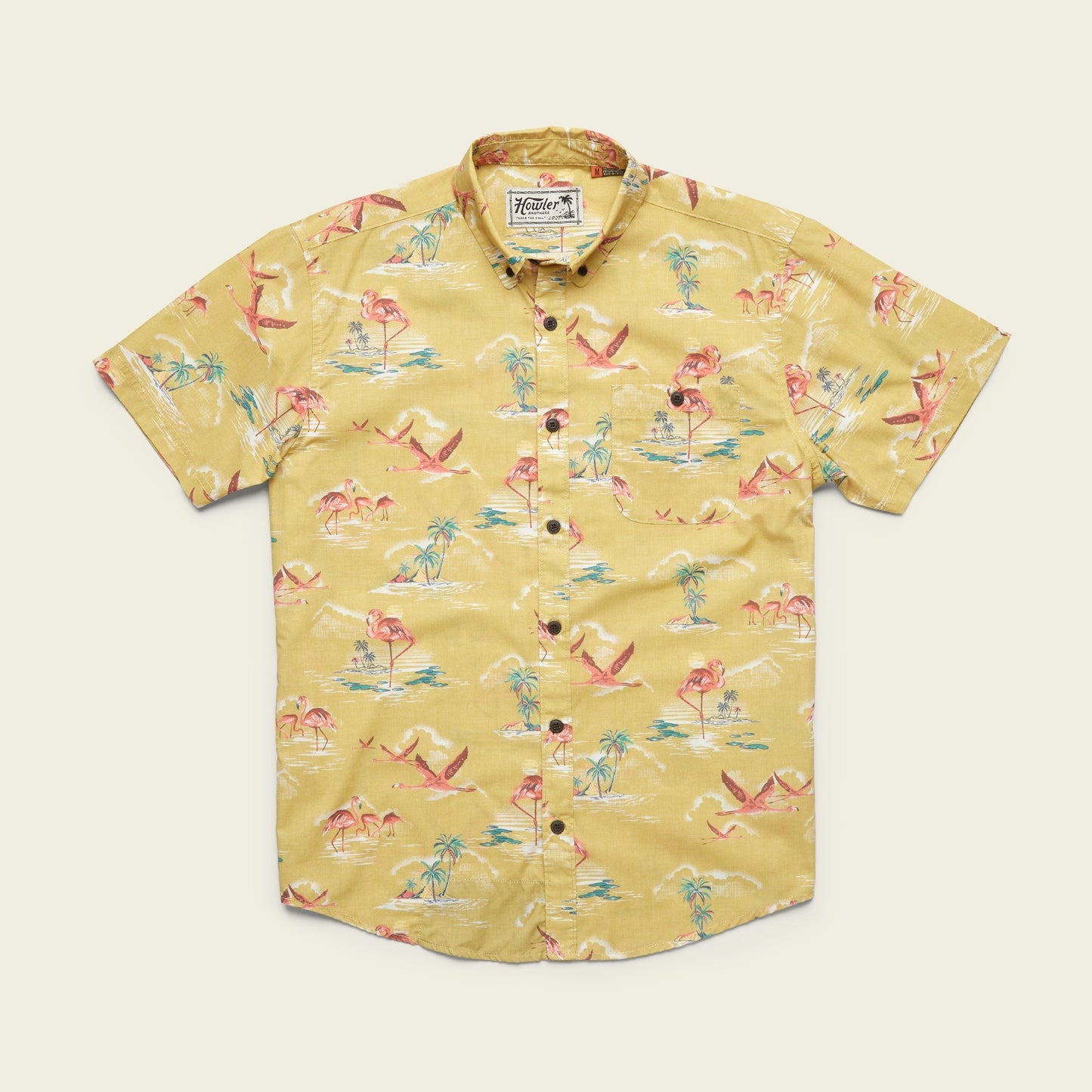 A lightweight cotton-poly Mansfield Shirt, this short-sleeve button-up features unique seasonal patterns with pink flamingos, palm trees, and blue water accents, laid flat on a cream background.