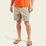 A person wearing an orange T-shirt, Pressure Drop Cord Shorts in stretch cotton corduroy with an elastic waistband, and brown sandals stands against a plain light background. Only the lower half of their body is visible.